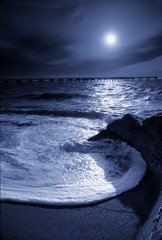 Wall Mural - beautiful night time photo illustration of a moonlit circular ocean wave and pier