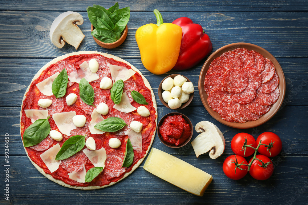 Pizza with ingredients on wooden  background
