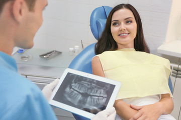 Wall Mural - Dentist looking at X-ray image of young female patient