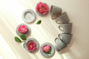 Poster - Composition of cups and saucers with flowers on light background