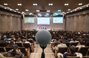 microphone over the abstract blurred photo of conference hall or seminar room with attendee backgrou