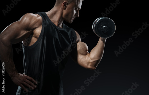 Zdjęcie XXL Moc sportowiec człowiek w treningu pompowania mięśni z hantle. Silny kulturysta z doskonałym mięśniem naramiennym, ramionami, bicepsami, tricepsem i klatką piersiową. Zakończenie mężczyzna sprawności fizycznej władza.
