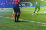 Fototapeta Sport - Lineman assistant referee with flag Officiate soccer game beside soccer field.