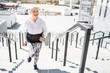 © Yakobchuk Olena - Cheerful aged woman training on steps with guard rails outdoors
