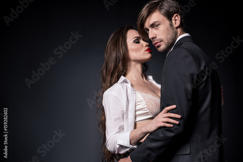Plakat młoda para zmysłowy, obejmując i stanie pocałować odizolowane na czarno