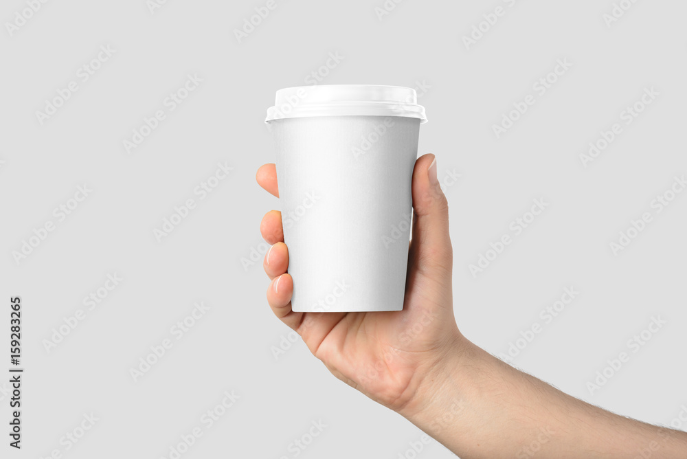 Mockup of male hand holding a Coffee paper cup isolated on light grey background.  - obrazy, fototapety, plakaty 