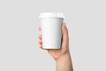 Mockup of male hand holding a Coffee paper cup isolated on light grey background. 