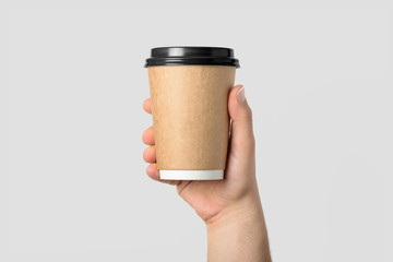 Mockup of male hand holding a Coffee paper cup isolated on light grey background. 