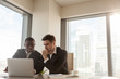 © fizkes - Two serious black and white businessmen discussing project sitting at office desk, using pc laptop, looking at screen, make presentation, create business plan, fulfill task, consider investment