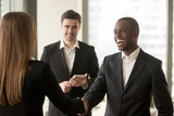 Fototapeta  - Happy smiling afro american businessman and caucasian businesswoman shaking hands standing in modern office, nice to meet you, first impression, congrats, promoted to the post, reward accomplishments