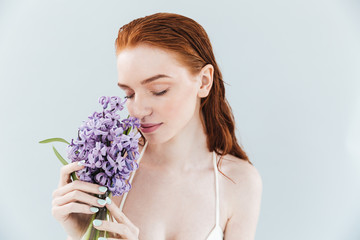 Canvas Print - Close up portrait of a ginger woman smelling hyacinth flowers