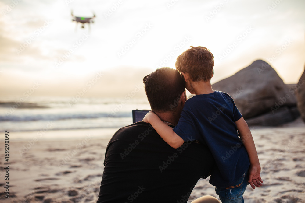 Father and son flying drone at the sea shore