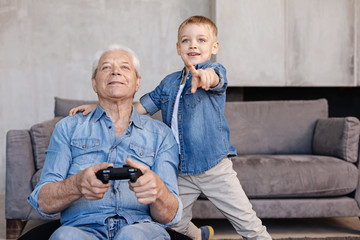 Active inspired man and his grandson enjoying new video game