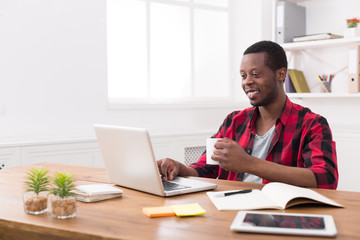 Wall Mural - Happy black businessman in casual office, work with laptop