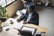 © LUMINA IMAGES - Overhead photo of African businessman sitting at his  and writing.