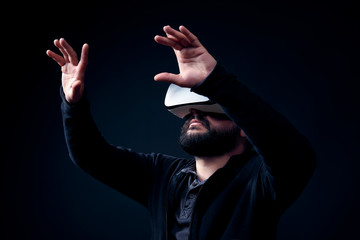 Poster - Young hipster bearded man wearing virtual reality goggles. Black background studio VR concept.