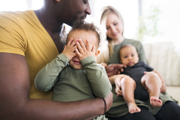 Young interracial family with little children at home.