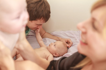 indoor portrait of young happy smiling mother and father with twin babies at home