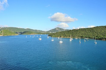 Wall Mural - Sailboats on the ocean with mountains in the background and a beautiful blue sky