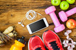 Fitness, healthy and active lifestyles Concept, dumbbells, sport shoes, bottle of waters, smartphone, jump rope and apples on wood background. copy space, top view