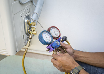 Technician is checking air conditioner with manometers, measuring equipment for filling air conditioners