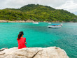 © Pangzz - asia woman wearing red shirt sitting on rock and looking scenery view. front of her have blue sea and green mountain are background. this image for nature,seascape,travel and portrait concept