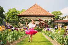 Sweet Little Kid Girl Dancing In A Beautiful Flower Garden On A Nice Sunny Summer Day, Wearing Bright Pink Tutu Skirt