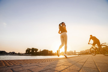 Wall Mural - Young runner female jogging over sunset