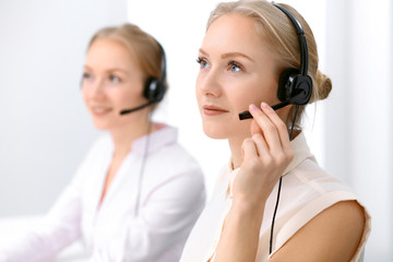 Call center. Focus on beautiful blonde woman in headset