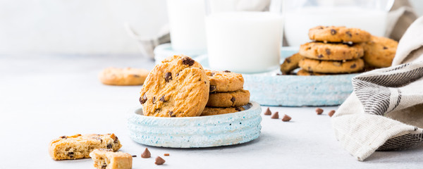 Wall Mural - Chocolate chip cookies on blue stone plate with glass of milk on light gray background. Selective focus. Copy space.