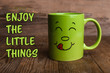 © Africa Studio - Text ENJOY THE LITTLE THINGS and cup with funny face on wooden background