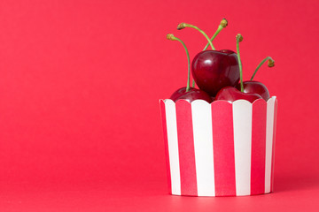 Wall Mural - cupcake with fresh red cherries on red background