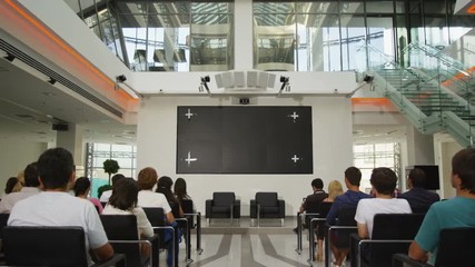 camera moves along pass between waiting for lecture listeners
