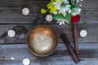© okrasiuk - Tibetan singing bowl and special sticks, burning candles and vase with flowers on the dark wooden background, top view. Selective focus