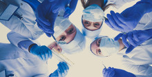 View from below of masked doctors looking at patient during examination .