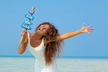 Wall Mural - Beautiful girl with handmade signpost in her hands on the beach