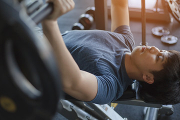 Young Asian man exercising in the fitness gym with flare light