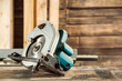 A modern green circular saw lies on a wooden table in the workshop. A close-up of a circular saw