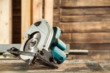 A Modern Green Circular Saw Lies On A Wooden Table In The Workshop. A Close-up Of A Circular Saw