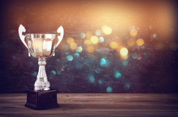 low key image of trophy over wooden table and dark background