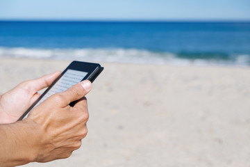 Wall Mural - man reading in a tablet or e-reader on the beach