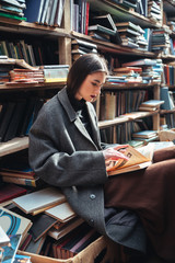 Portrait of a woman reading book in an old library