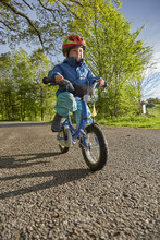 Boy Wearing Red Cycle Helmet Cycling On Rural Road