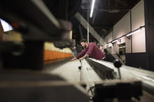 Young Male Weaver Working At Old Weaving Machine In Textile Mill