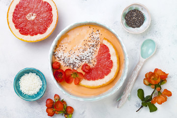 Wall Mural - Healthy breakfast set. Superfoods smoothie bowl with chia seeds, coconut, grapefruit and quince flowers. Overhead, top view, flat lay.