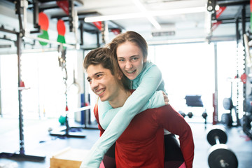 Wall Mural - Young man in gym carrying woman on his shoulders.