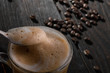 Coffee spoon with foam, coffee beans on the background, dramatic mood