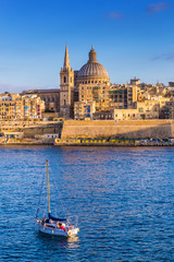 Wall Mural - Valletta, Malta - St.Paul's Cathedral in golden hour at Malta's capital city Valletta with sailboat and beautiful blue sky