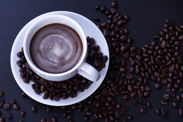 Hot coffee in the white cup and roasted on dark background
