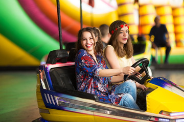 Happy girlfriends driving a bumper car and having great fun